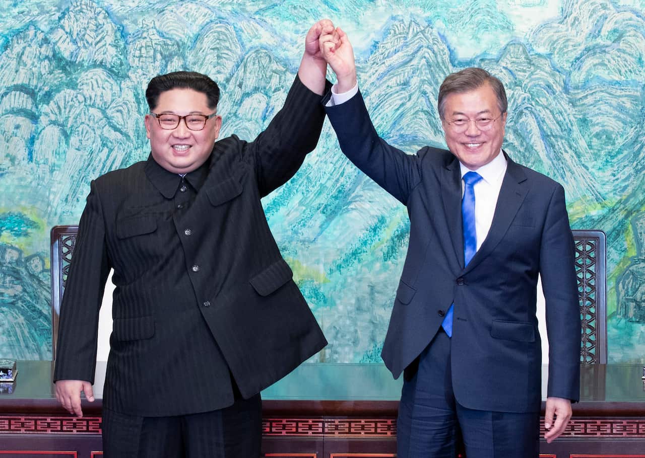 North Korean leader Kim Jong-Un and South Korean President Moon Jae-In join hands after signing a document at the Joint Security Area on the DMZ.