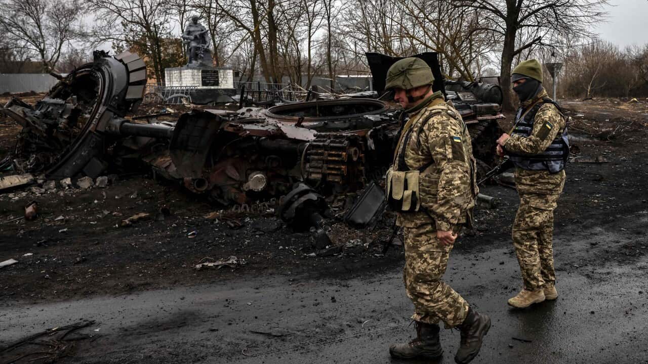Ukrainian soldiers patrol next to a destroyed Russian tank in the village of Lukianivka near Kyiv on 30 March, 2022.