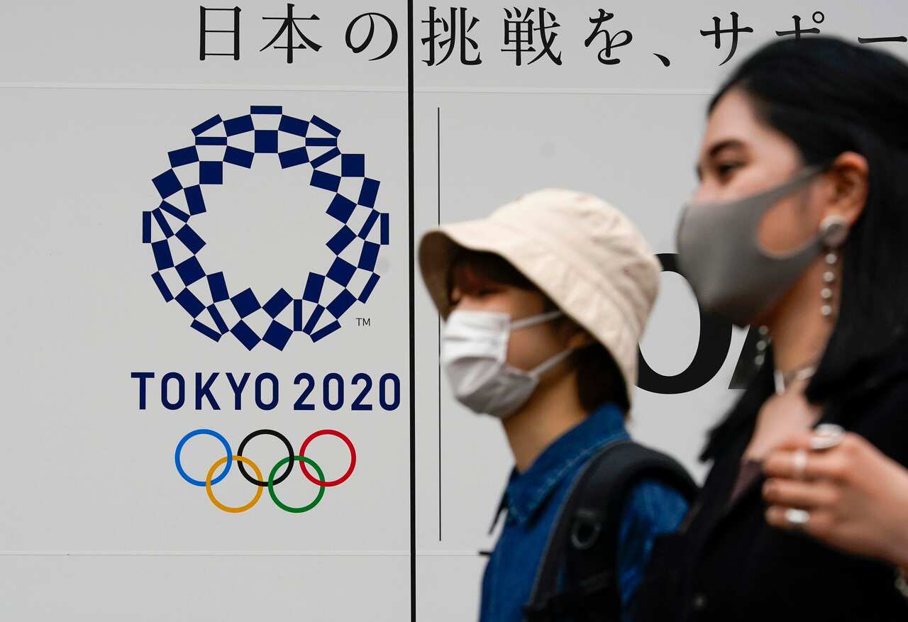 Pedestrians walk past the logo of Tokyo 2020 Olympic Games in Tokyo, Japan, 19 May 2021.