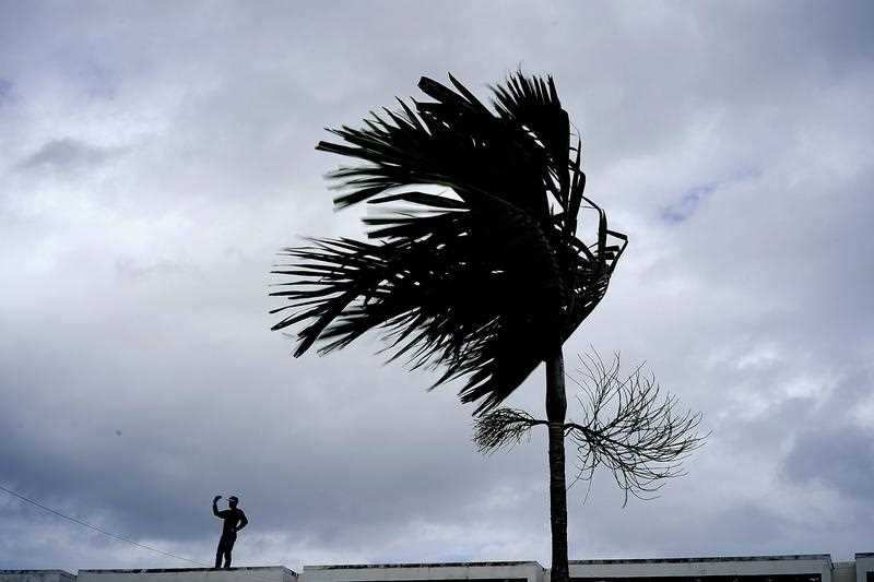 A man stands on a store's roof as he works to prepare it for the arrival of Hurricane Dorian in Freeport on Grand Bahama