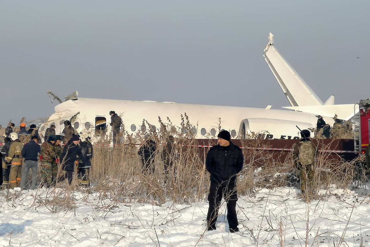 Police stand guard as rescuers work on the side of a plane crash near Almaty International Airport, outside Almaty, Kazakhstan.