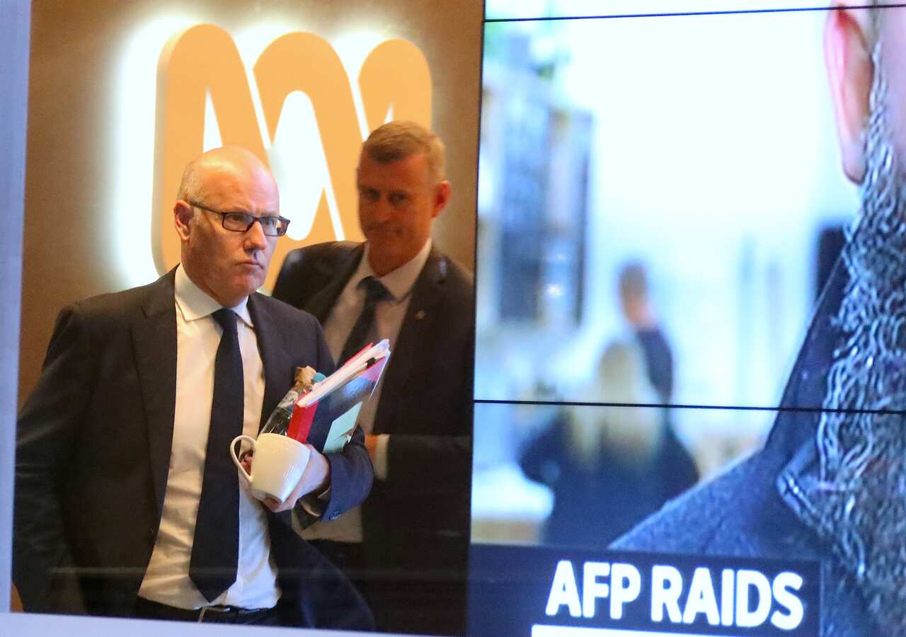 John Lyons (left), Executive Editor of ABC News, is followed by an AFP officer as they walk out the main entrance to the ABC building, Sydney, June 5, 2019.