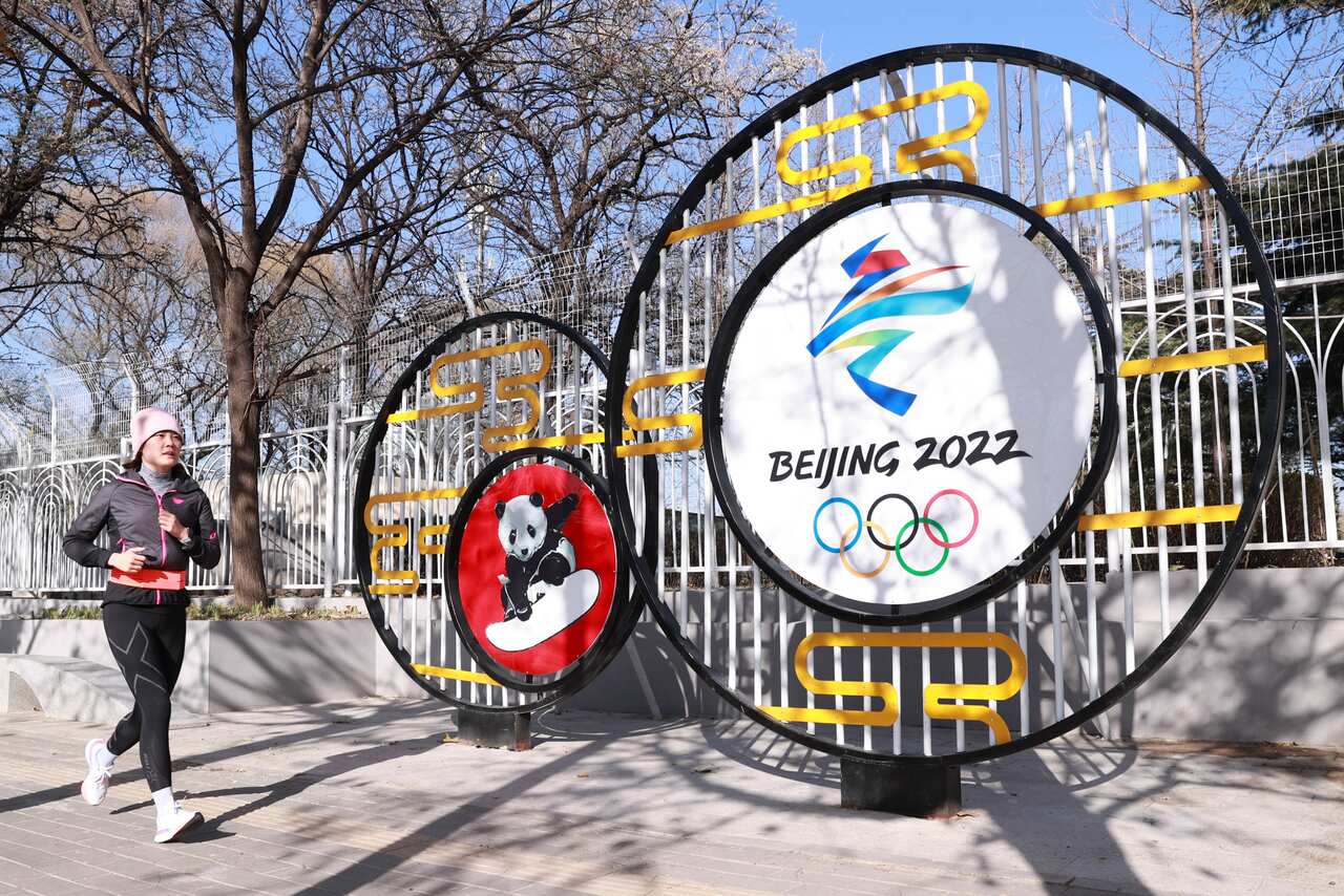 A jogger runs by a street decoration for the Beijing 2022 Winter Olympics at National Olympic Sports Center on 24 November, 2021 in Beijing, China. 