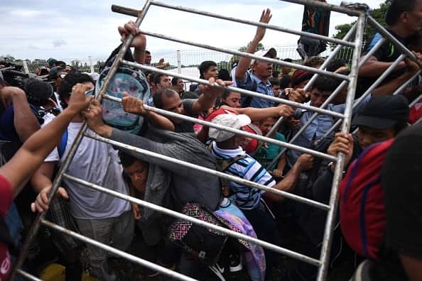 Honduran migrants remove a barrier at the Guatemala-Mexico international border bridge.