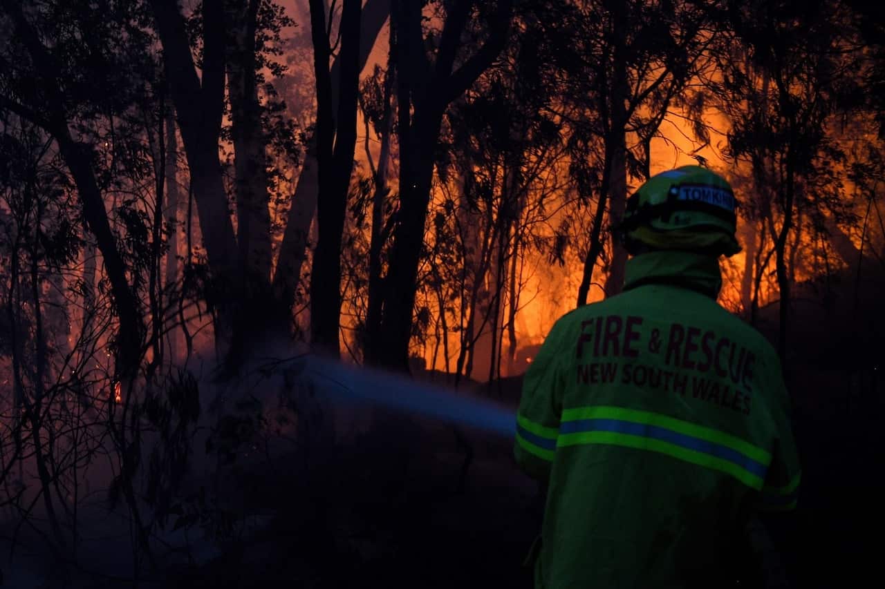 Fire and Rescue NSW firefighters conduct property protection as a bushfire burns close to homes on Railway Parade in Woodford NSW, Friday, November 8, 2019. 