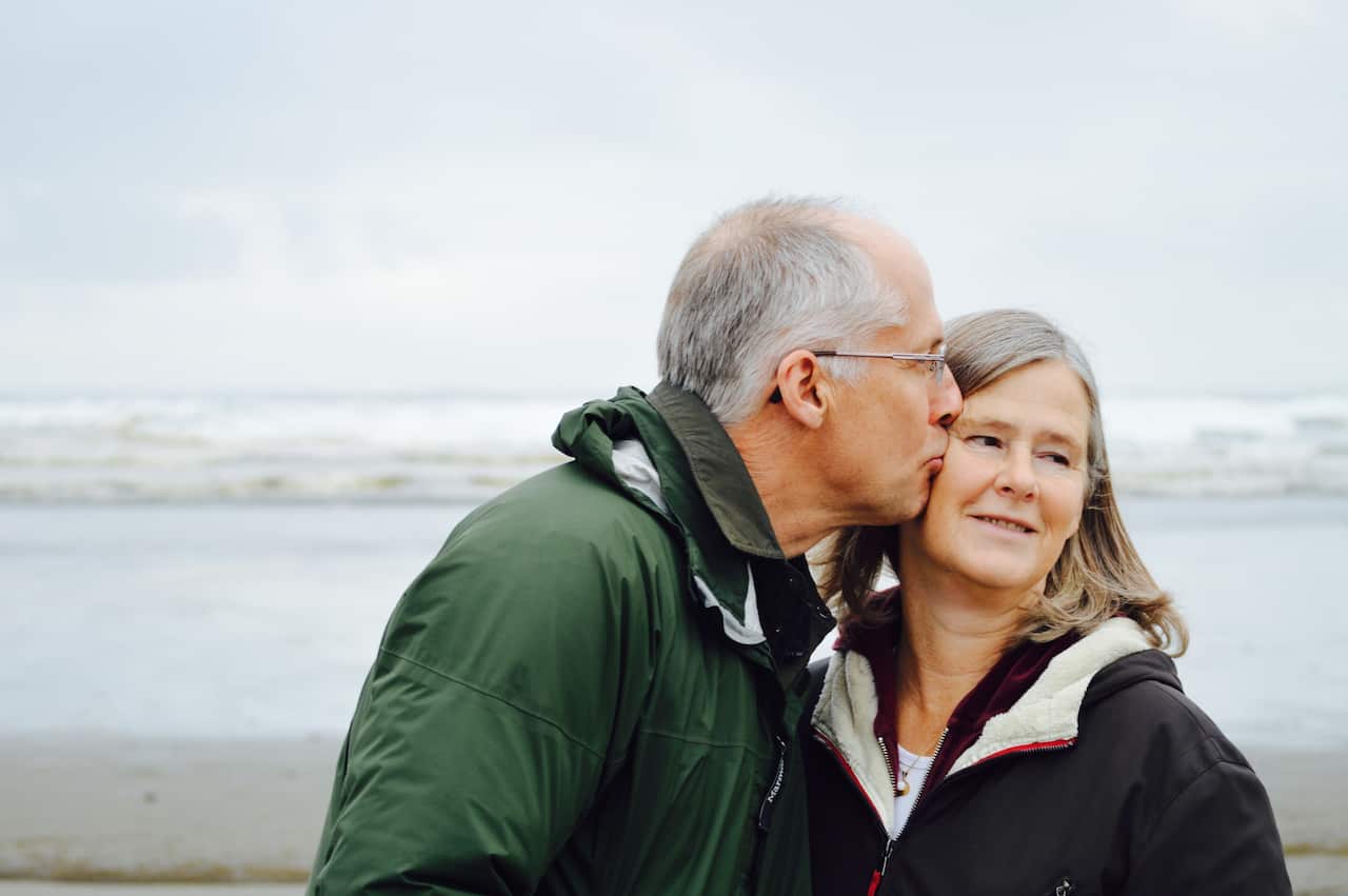 old couple kissing on a beach