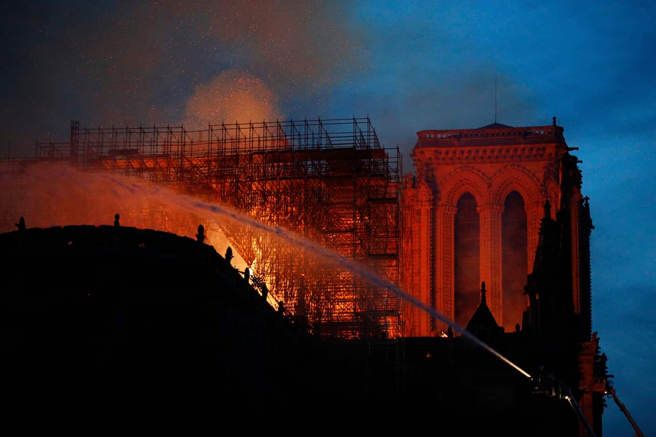 Firefighters use hoses as Notre Dame cathedral burns in Paris.