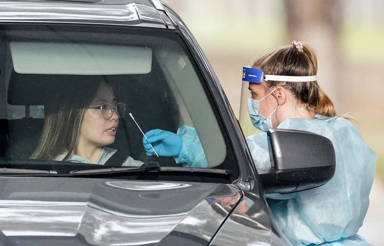 A medical worker takes a sample from a person at a drive-through COVID-19 pop-up testing clinic at the Keilor Community Hub in Melbourne