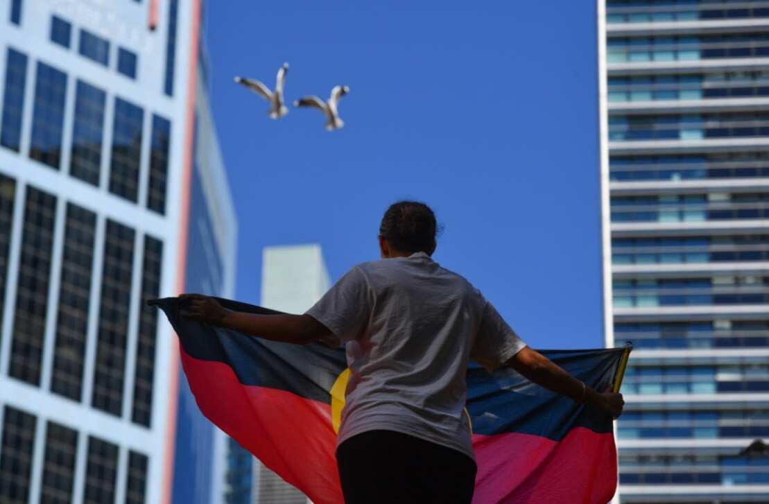 A protester holds an Aboriginal flag at the Black Deaths in Custody Rally at Town Hall in Sydney, Saturday, April 10, 2021.