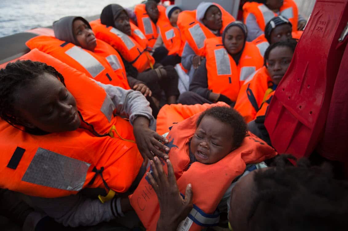 File image: migrants and refugees are assisted by members of the Spanish NGO Proactiva Open Arms, as they crowd aboard a wooden boat sailing out of control in the Mediterranean Sea about 21 miles north of Sabratha, Libya (AAP).jpg