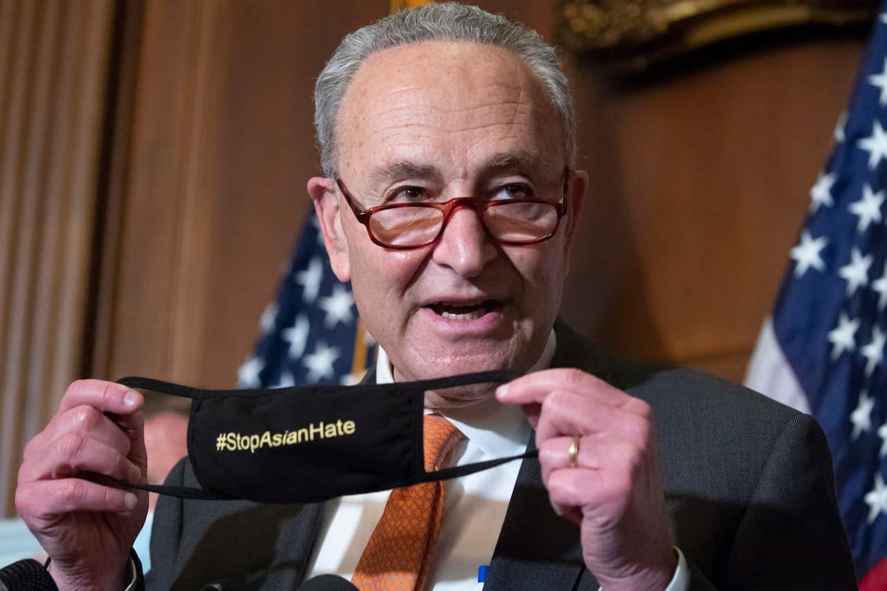 Senate Majority Leader Chuck Schumer holds up a face mask that reads 'Stop Asian Hate' after the Senate passed the COVID-19 Hate Crimes Act