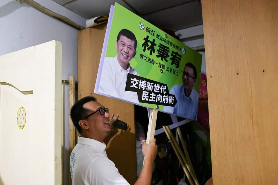 Lin Ping-yu, 38, poses holding one of the posters for his campaign from the storage of his office in New Taipei City, Taiwan, May 31,2022.