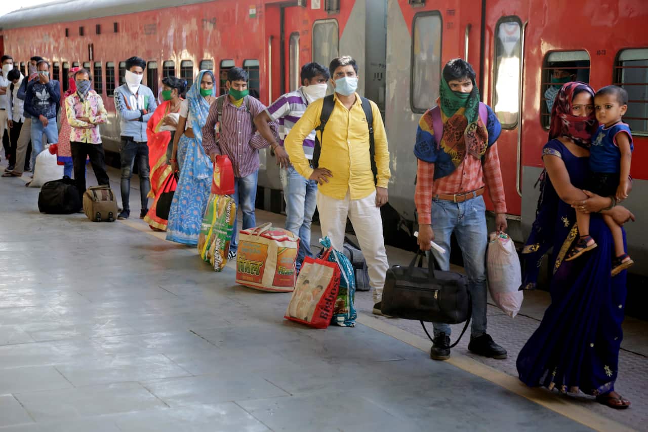 Indian migrated workers stands in queue to board a special train at a railway station in Ahmedabad, India.