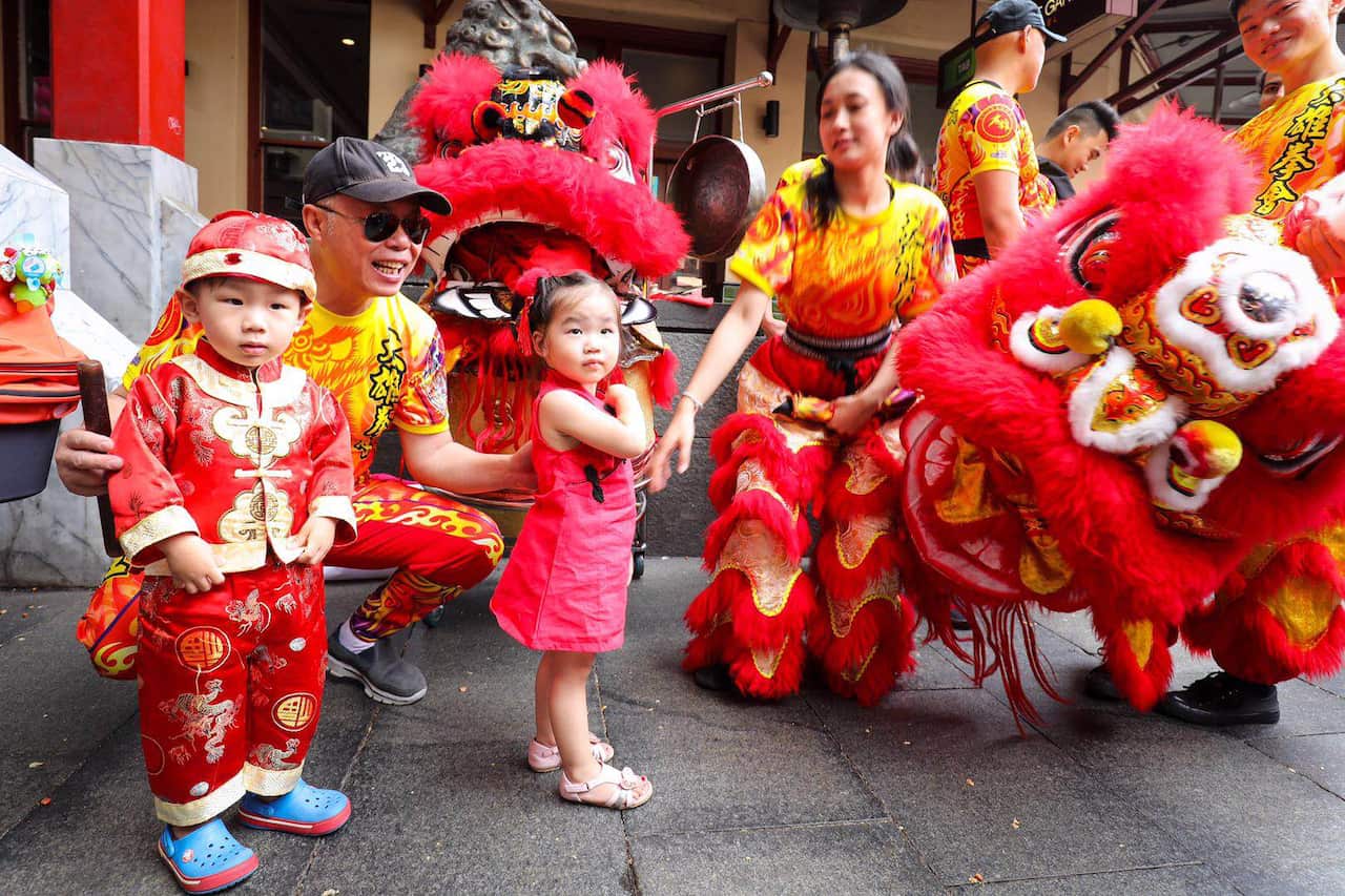 As crianças vestem-se a rigor e recebem envelopes vermelhos dos seus pais