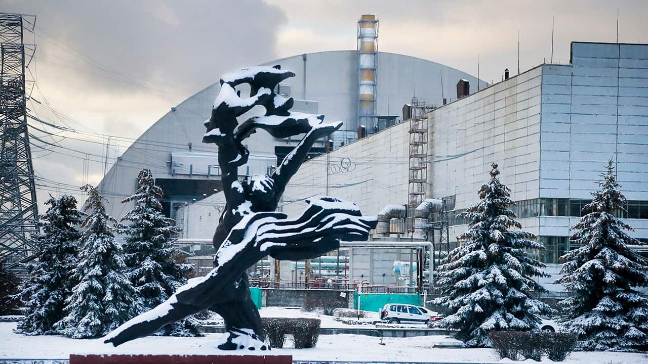 Тhe monument to the victims of the Chernobyl tragedy is in front of a new shelter installed over the exploded reactor, Ukraine, Nov. 29, 2016.