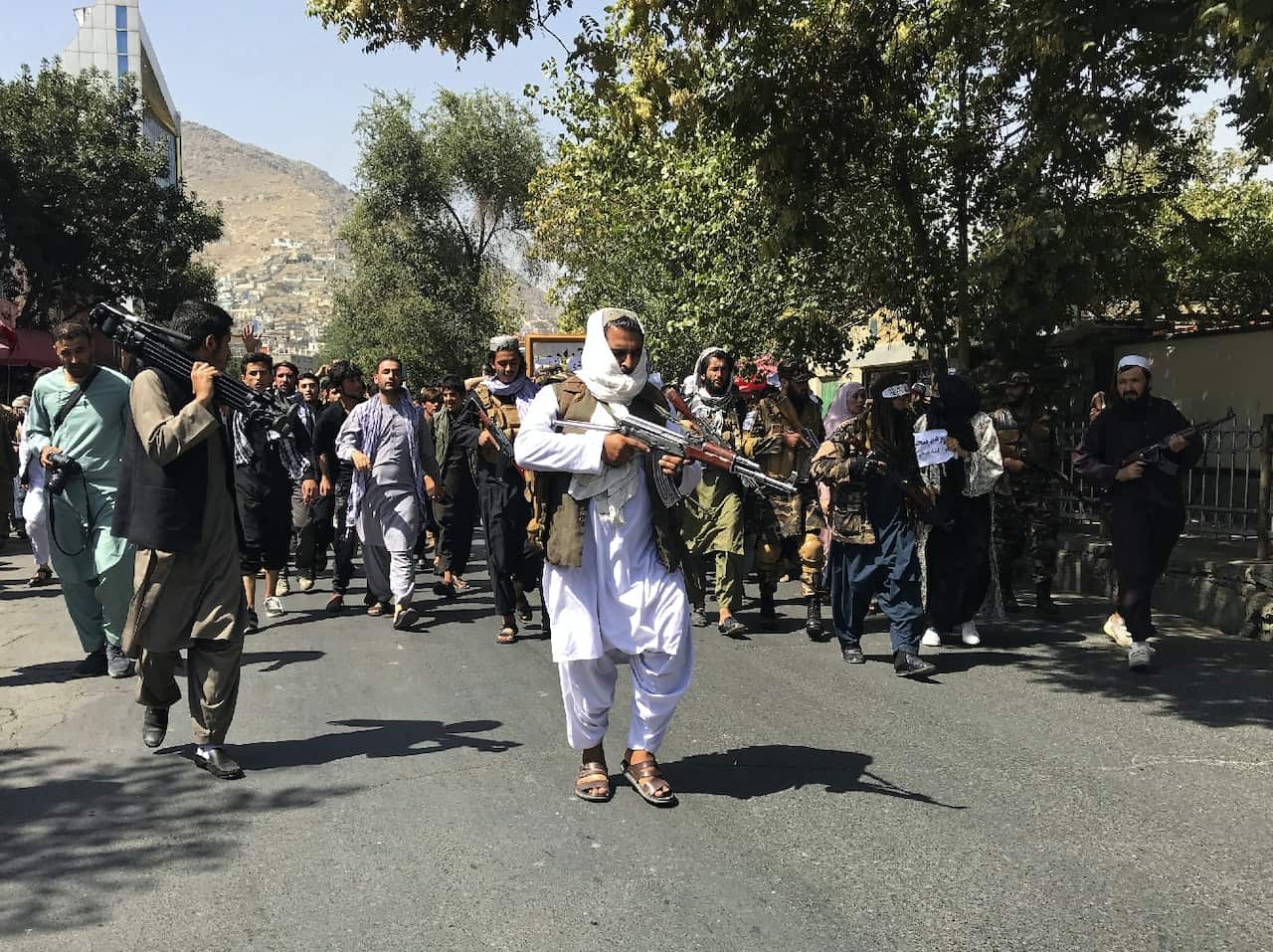 Taliban soldiers walk towards Afghans protesting in Kabul.