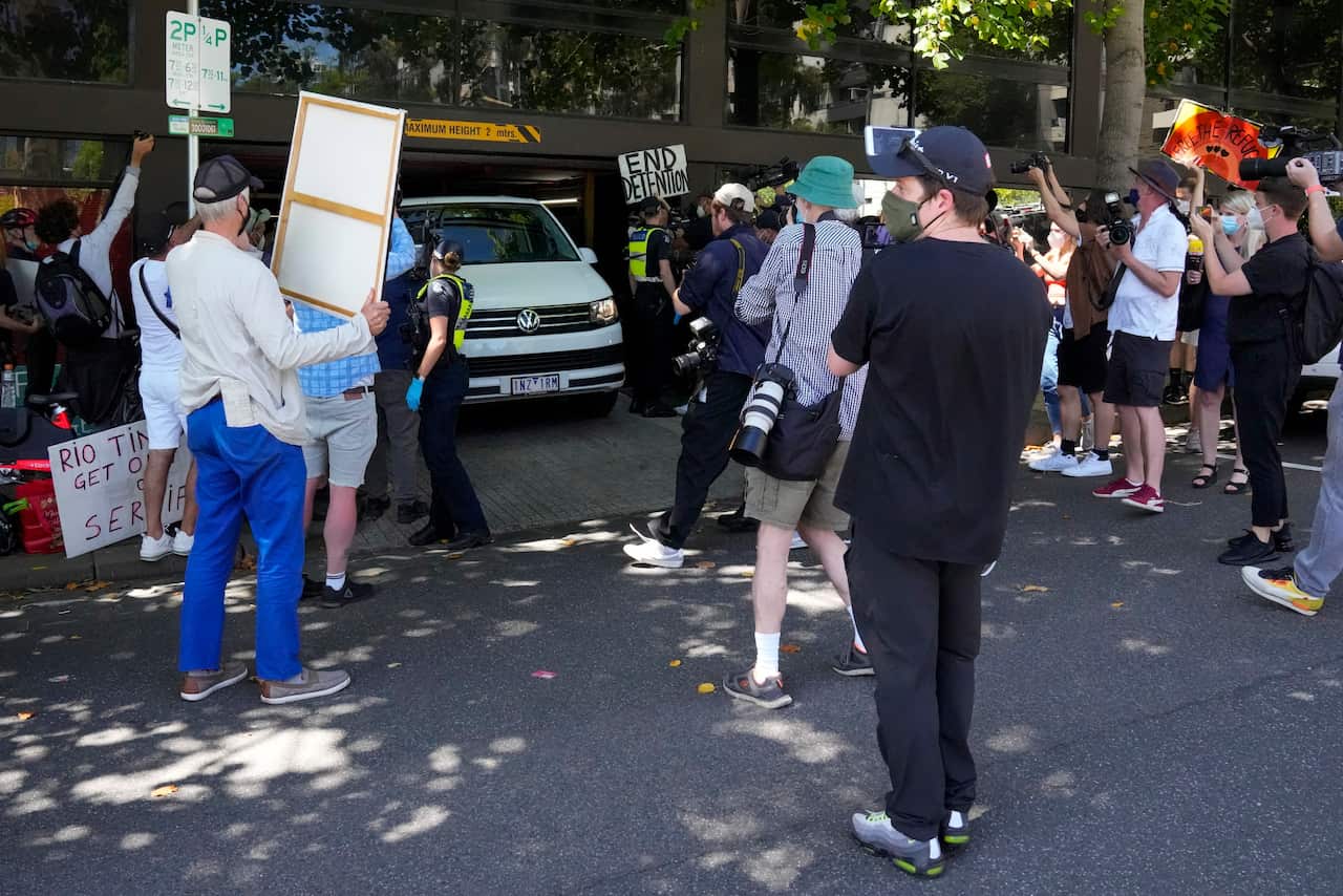 Camera crews surround a van as it leaves the Park Hotel on Monday 10 January 2022