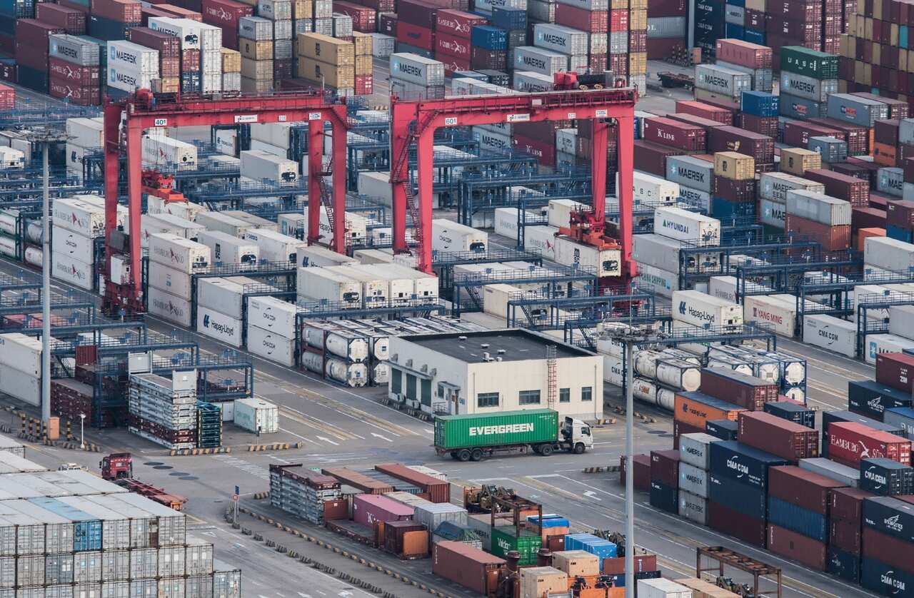 A cargo truck drives amid stacked shipping containers at the Yangshan port in Shanghai, Thursday, March 29, 2018. 