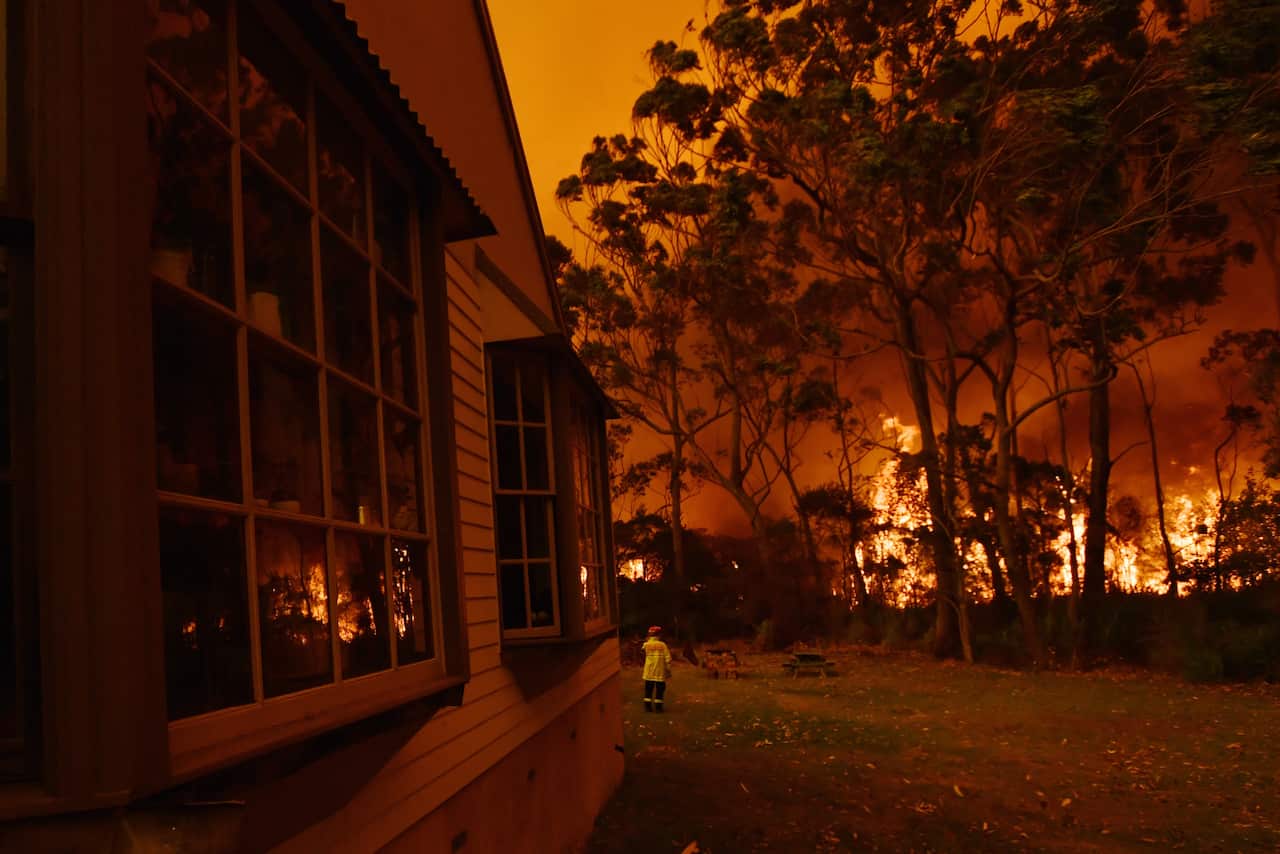 Firefighting crews battle a bushfire encroaching on properties near Lake Tabourie on the Princes Highway between Batemans Bay and Ulladulla. 
