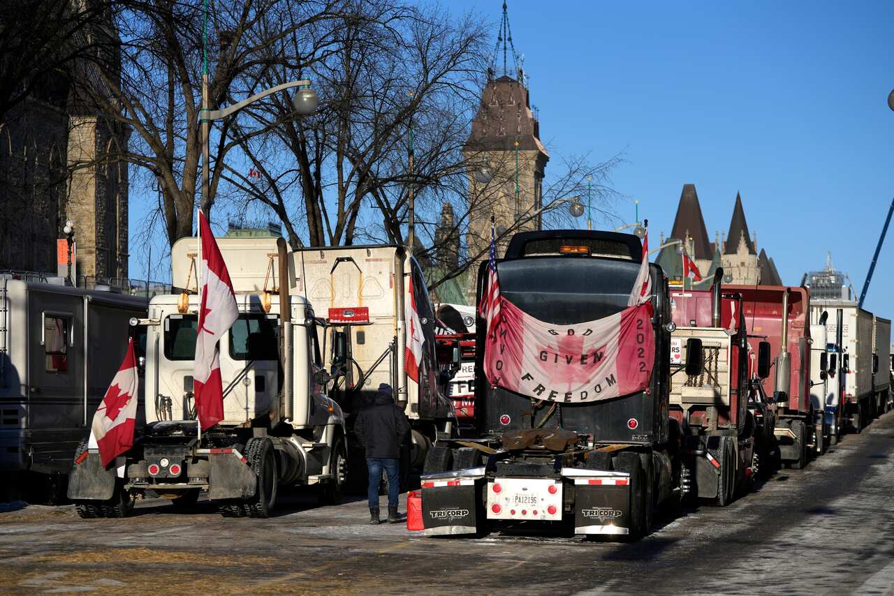 A person walks among trucks flying Canadian flags