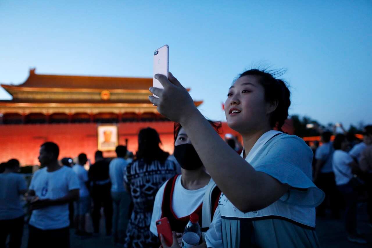 Visitors use mobile phones at Tiananmen Square in Beijing.