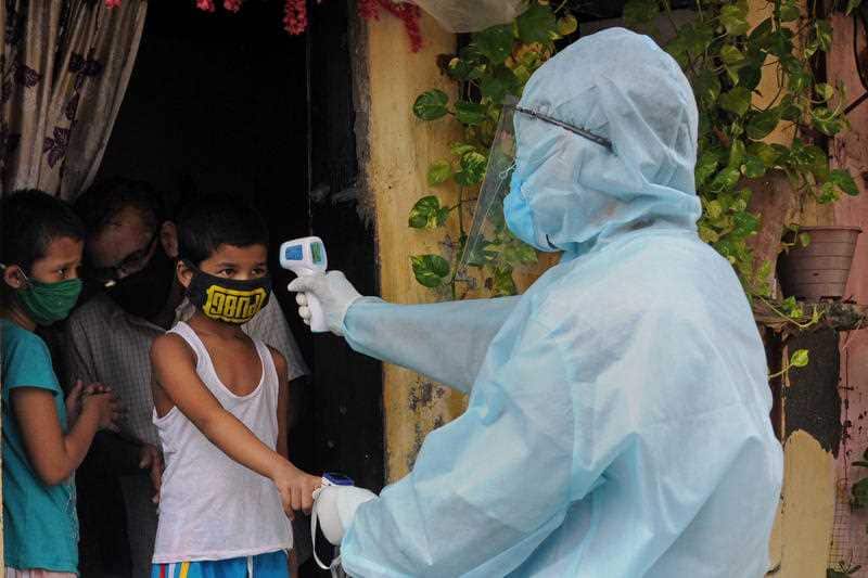 A healthcare worker checks the body temperature of a boy during a free coronavirus screening in Mumbai