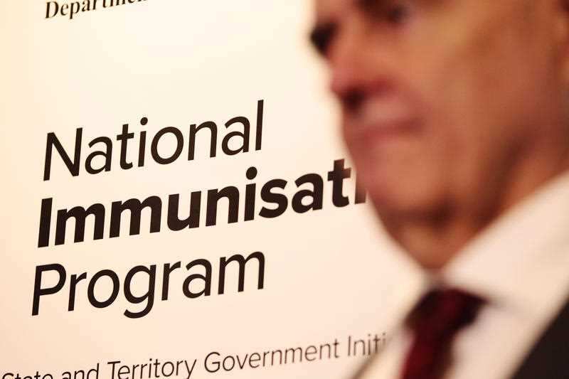 A National Immunisation Program sign is seen behind Australia's Chief Medical Officer Professor Brendan Murphy during a visit to SIA Medical Centre.