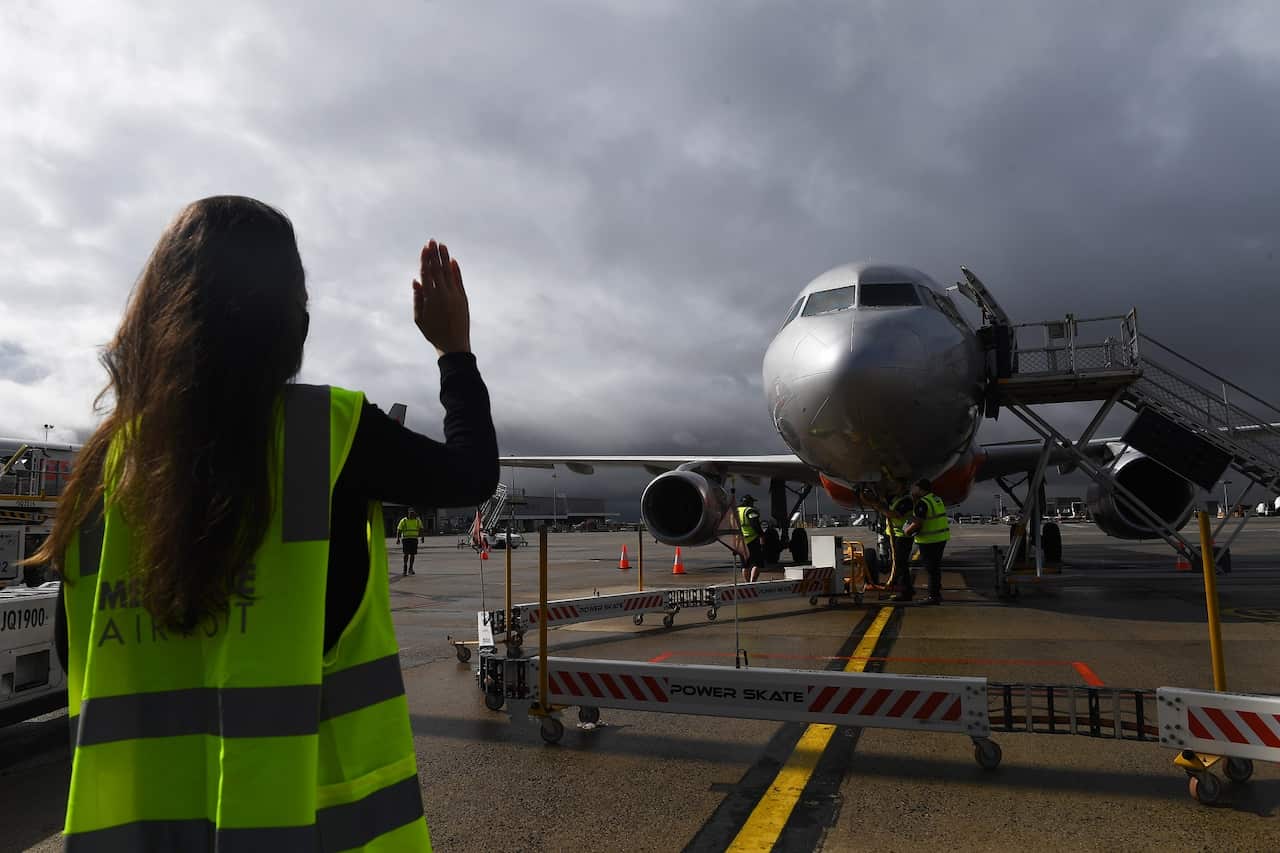 A Melbourne Airport staff member waves to a pilot in a Sydney-bound Jetstar plane at Melbourne Airport on 23 November 2020.