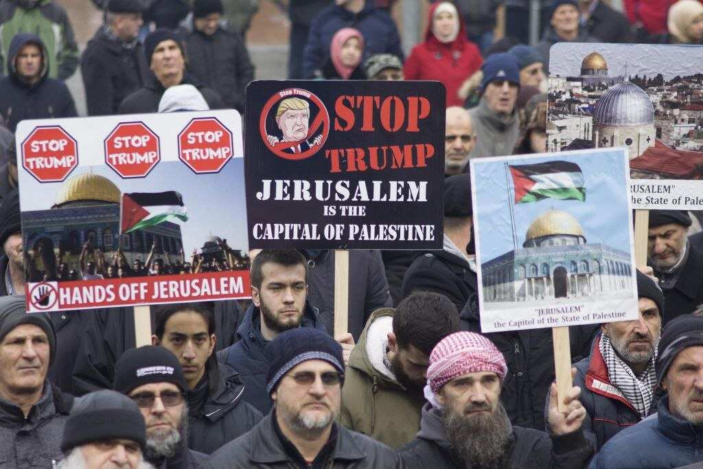People in Bosnia and Herzegovina hold banners during a protest against Donald Trump's announcement.