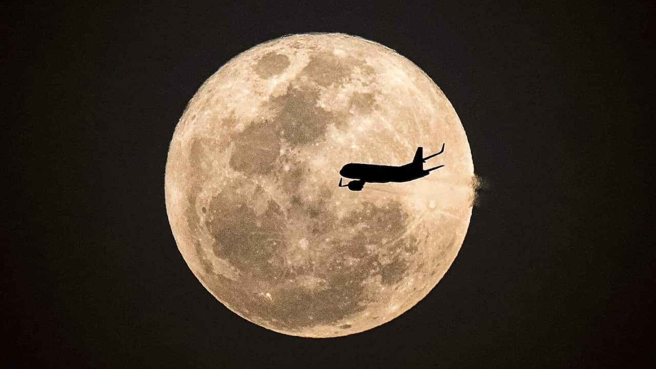 Aircraft fly pass Supermoon at night