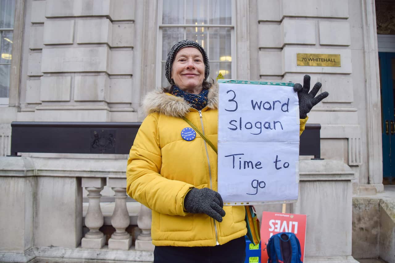 A demonstrator holds a 'Time To Go' placard outside the Cabinet Office