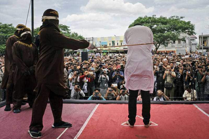 A Shariah law official whips a man convicted of gay sex during a public caning in Banda Aceh, Aceh province. Homosexuality is illegal in the province.