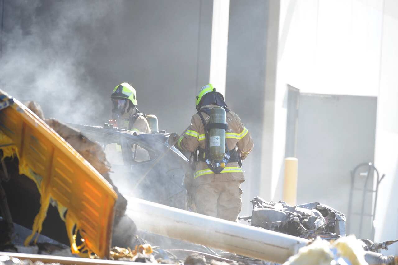 Fire crew at the scene where a light plane crashed into the back of a DFO building at Essendon airport in Melbourne.