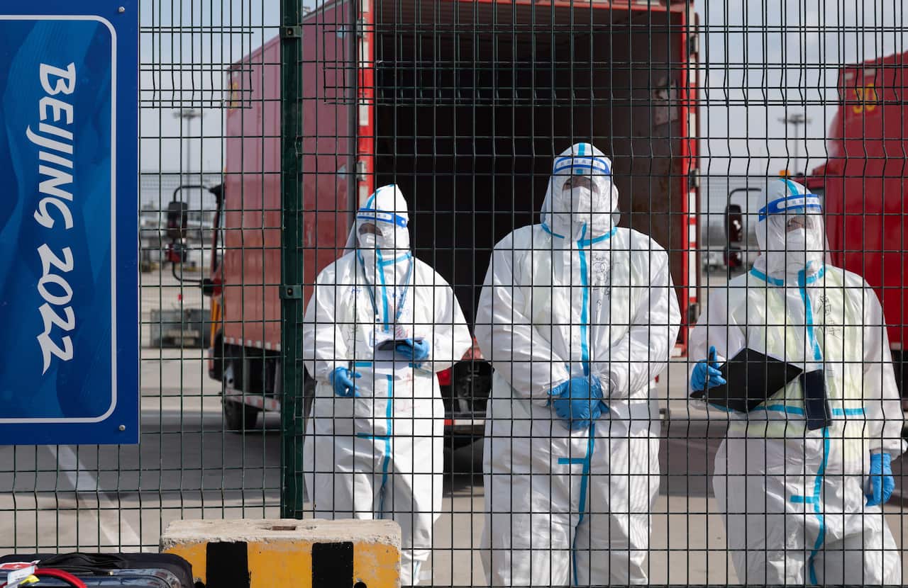 epa09719676 Staffs wearing protective gears stand next an Olympics sign at the Beijing International Airport in China, 31 January 2022. The Beijing 2022 Winter Olympics is scheduled to start on 04 February 2022.  EPA/JEON HEON-KYUN