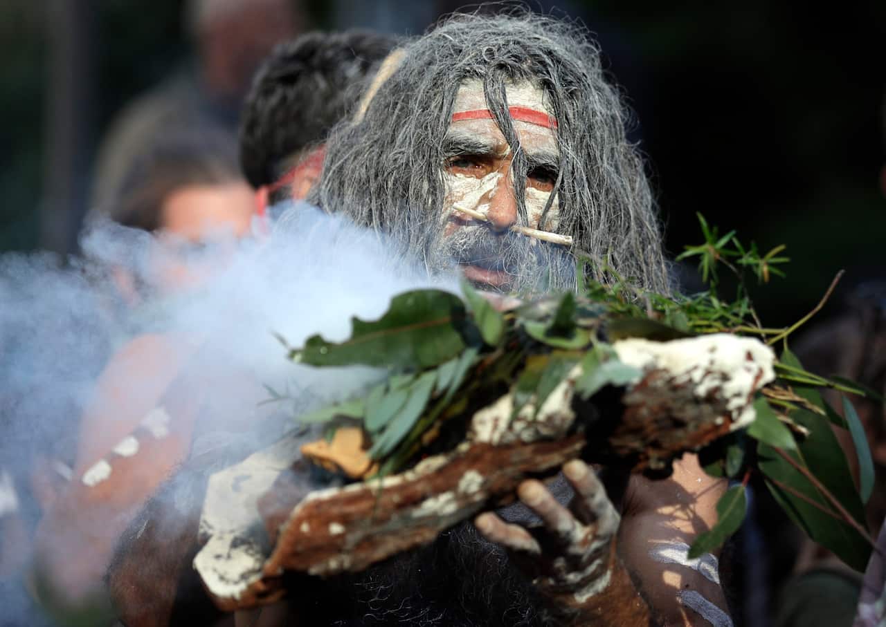 An Aboriginal man performs a smoking ceremony as protesters gather in Sydney, Saturday to support the movement of US protests.