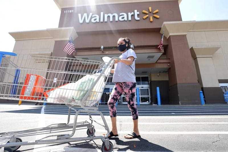 A Walmart shopper wears a mask as protection against the coronavirus as she exits a Walmart Supercenter in Fairfax, Virginia.
