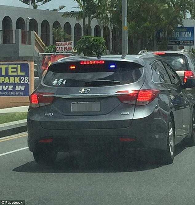 Two adult stickers and one child sticker were adhered to the corner of the window, with flashing blue and red lights the only things identifying it as a police vehicle