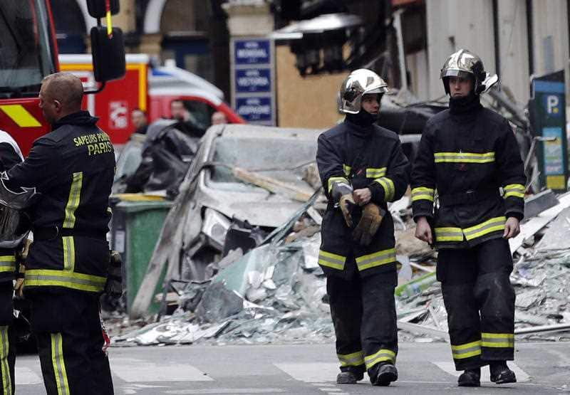 Firefighters stand on the scene of a gas leak explosion in Paris.