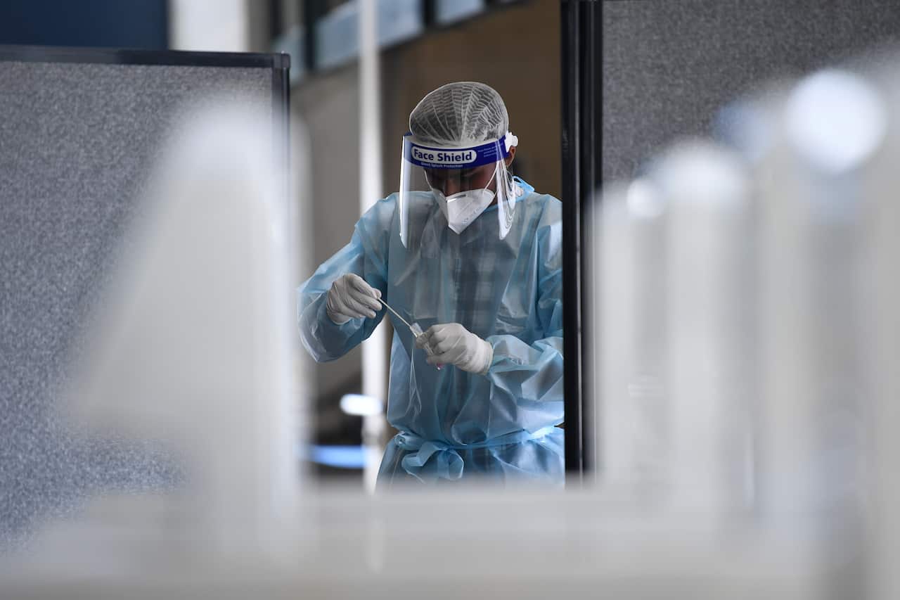 A healthcare worker handles a cover swab at a pop up testing facility at the MCG stadium in Melbourne, Wednesday, January 6, 2021
