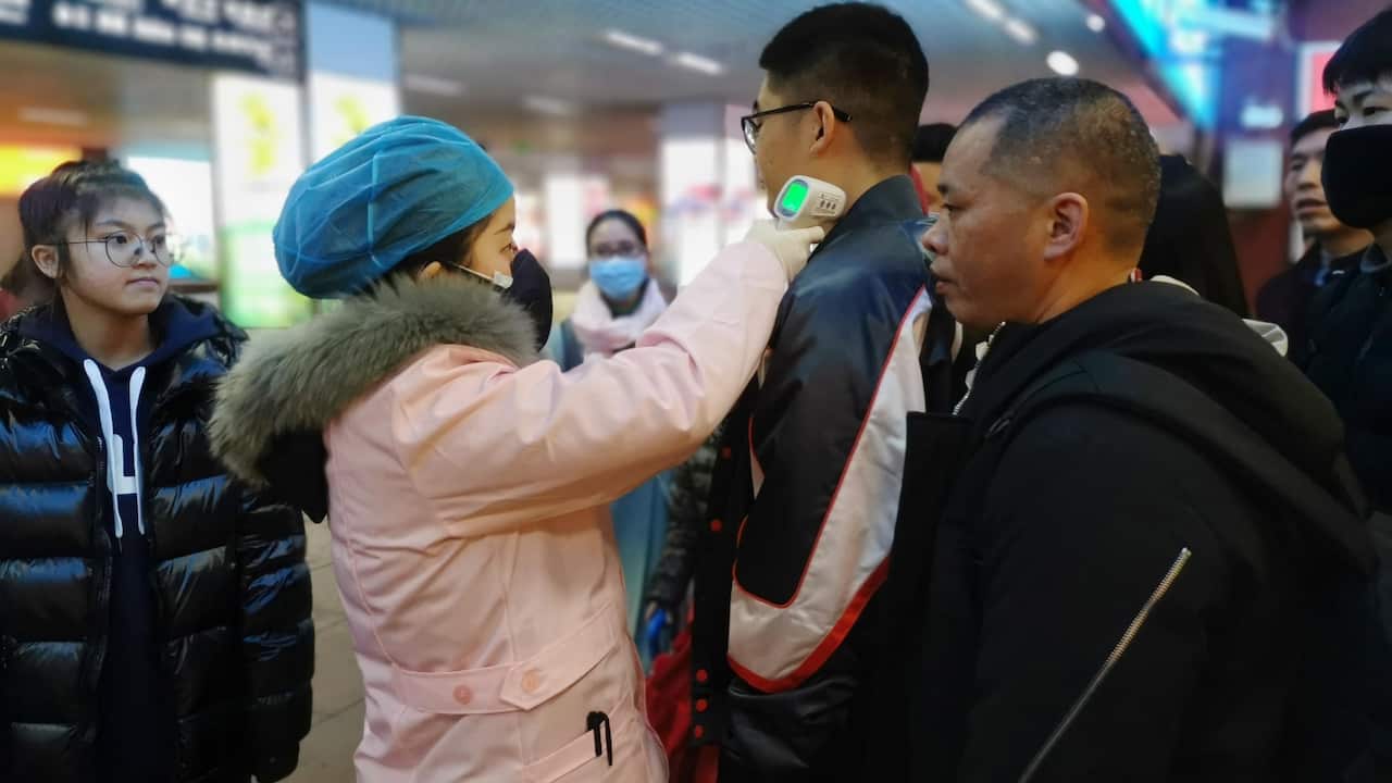 Passengers have their body temperature checked as they arrive at a railway station in Yingtan City, Jiangxi province.