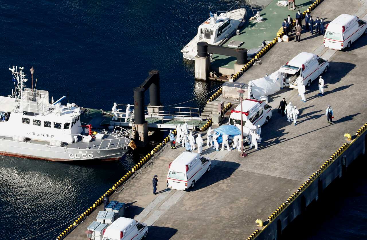 Health officials and Japanese Coast Guard members transfer infected passengers from the cruise ship.