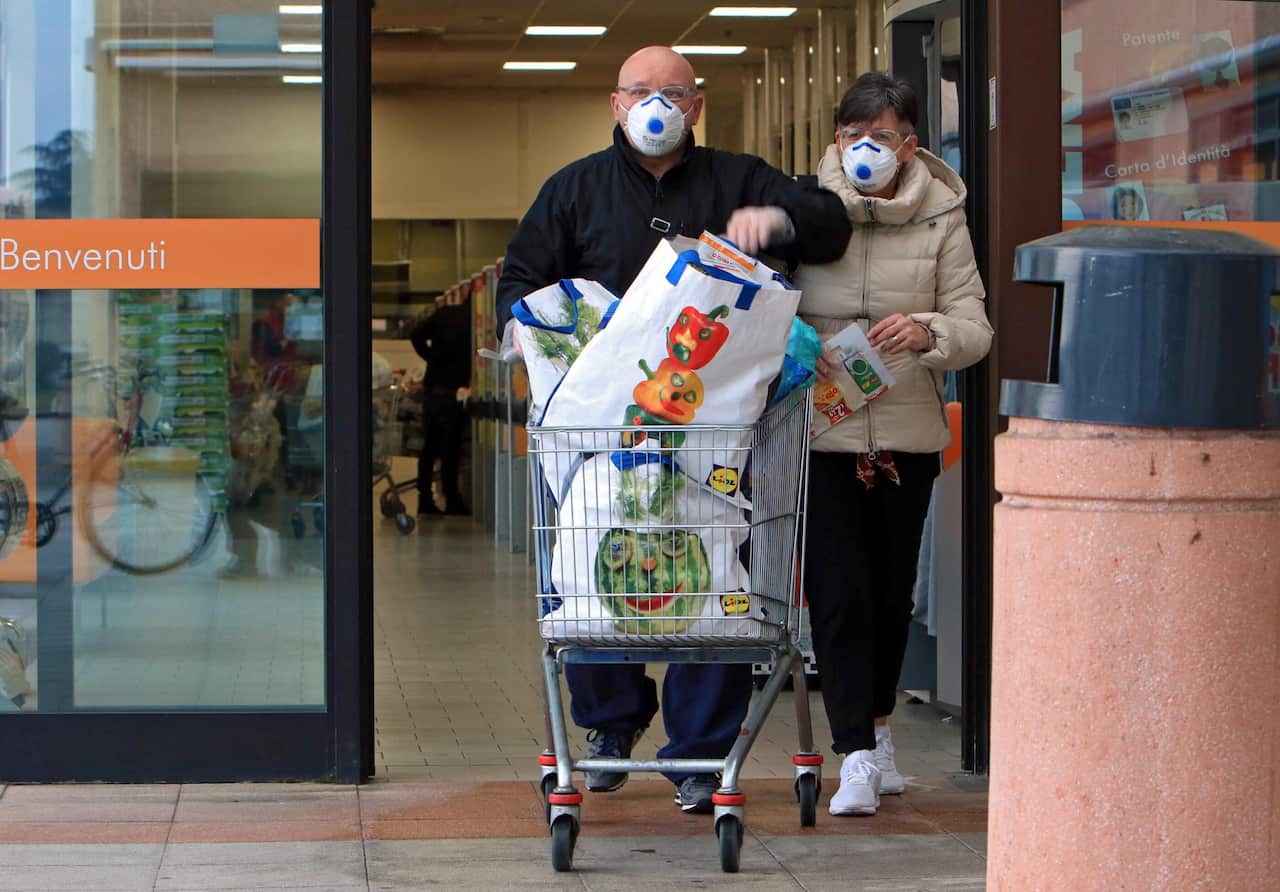 People wearing protective face masks shop at a supermarket in Casalpusterlengo, one the northern Italian towns placed under lockdown.