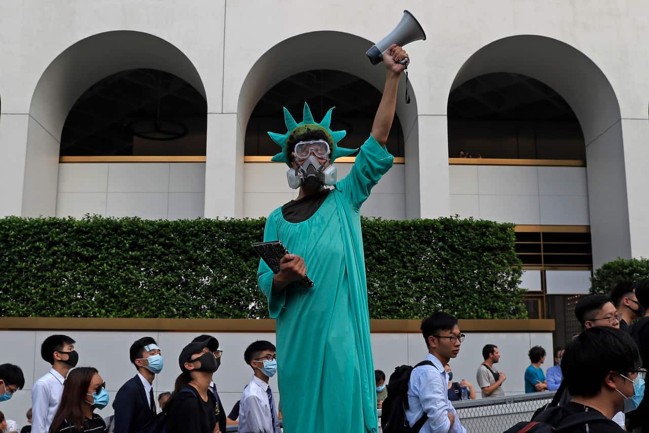 A protester dressed as the Statue of Liberty poses as people march to the US Consulate in Hong Kong 