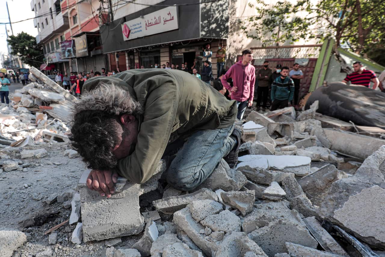 Palestinians evacuate children, women, and the elderly from under the rubble of their destroyed home after an Israeli air raid on Gaza City, on 16 May.