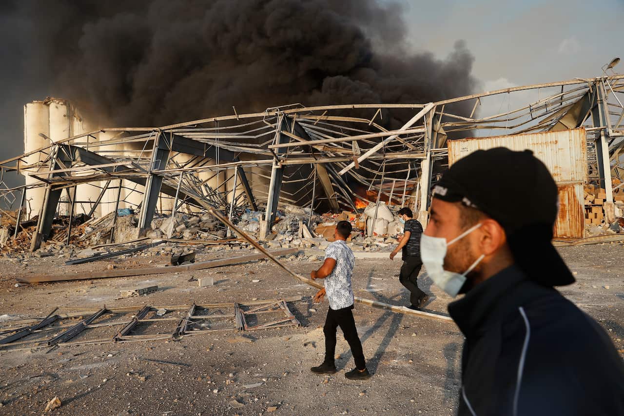 Lebanese port workers walk at the explosion scene that hit the seaport of Beirut, Lebanon, Tuesday, 4 August, 2020. 