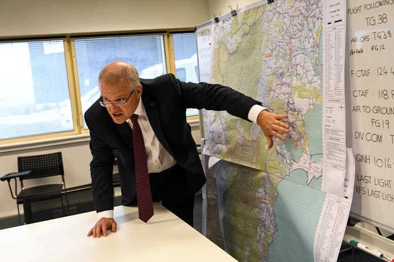 Prime Minister Scott Morrison takes a look at a map of an area impacted by bushfire during an operational update in Nowra, Sunday 5 January, 2020