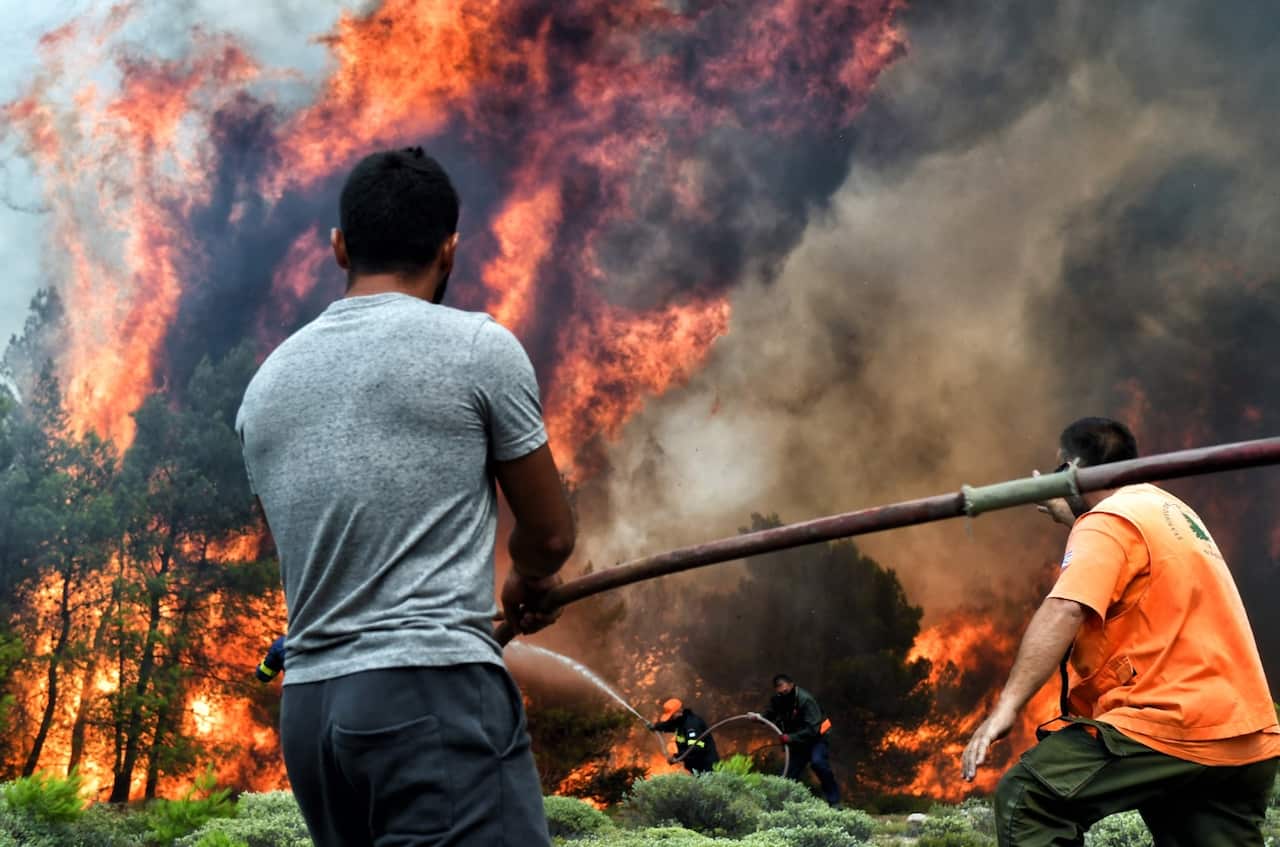 Firefighters and volunteers try to extinguish a wildfire raging in Verori, near Loutraki city, Peloponnese, southern Greece, 24 July 2018. 