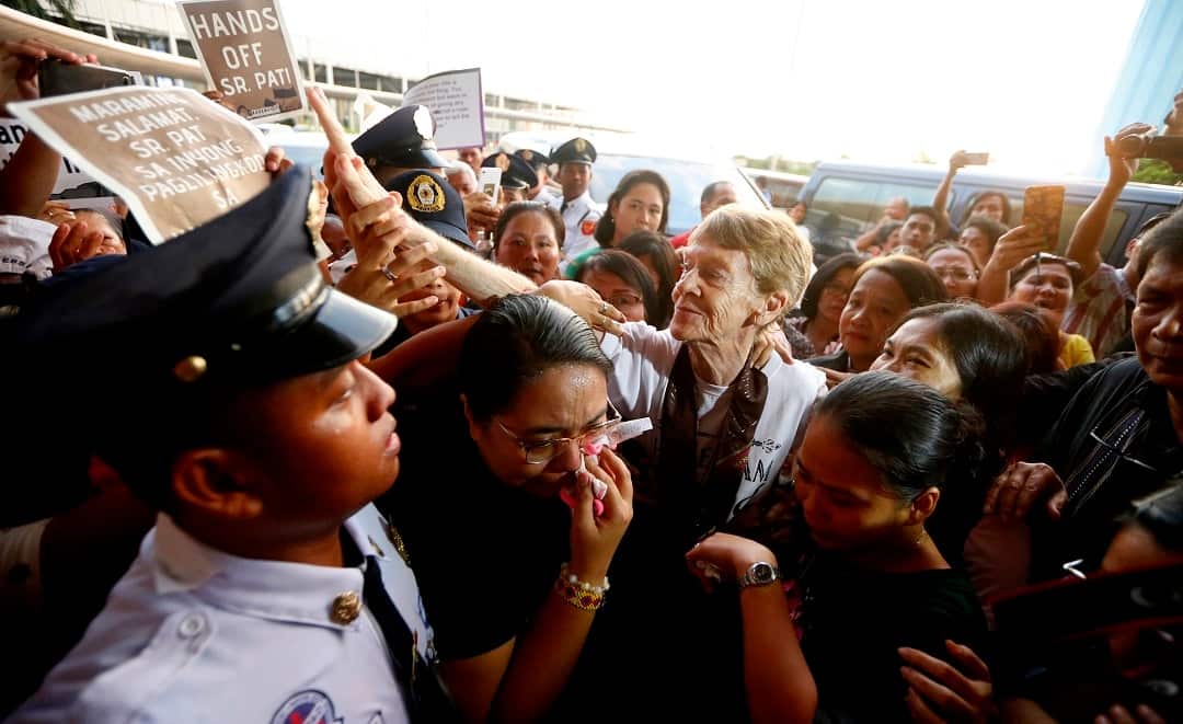 Australian nun Sister Patricia Fox is surrounded by supporters and media as she leaves the Philippines. 