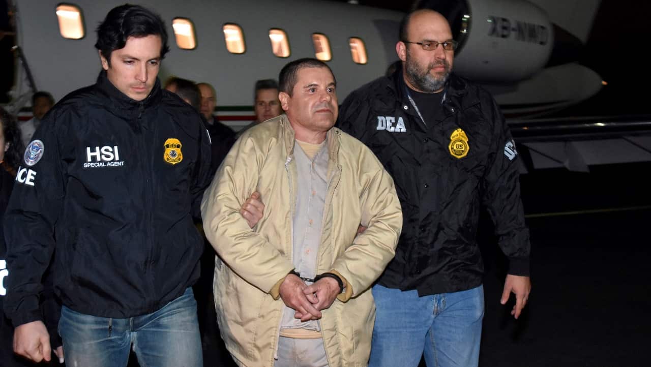 Authorities escort Joaquin "El Chapo" Guzman, center, from a plane to a waiting caravan of SUVs at Long Island MacArthur Airport.