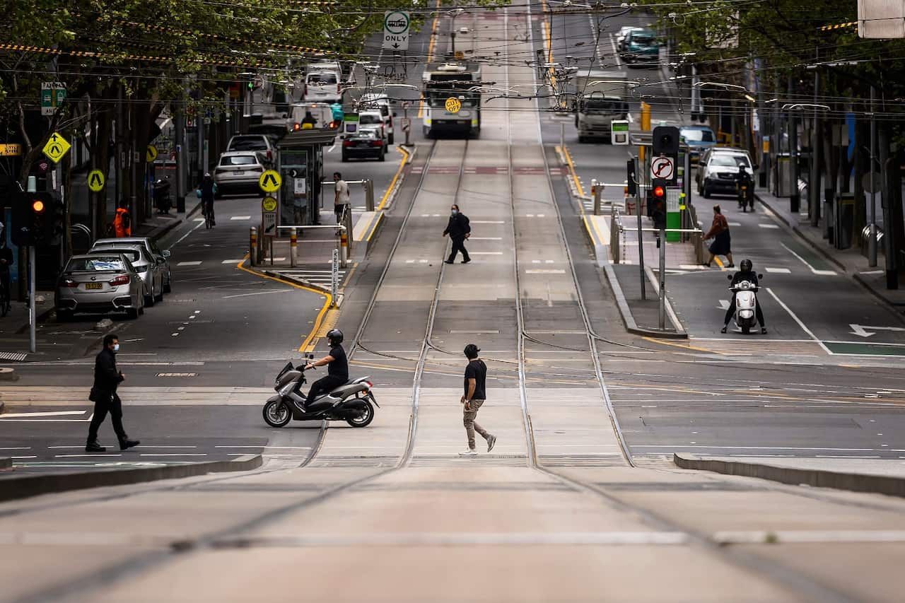 People are seen crossing Collins Street in Melbourne, the world's most locked-down city